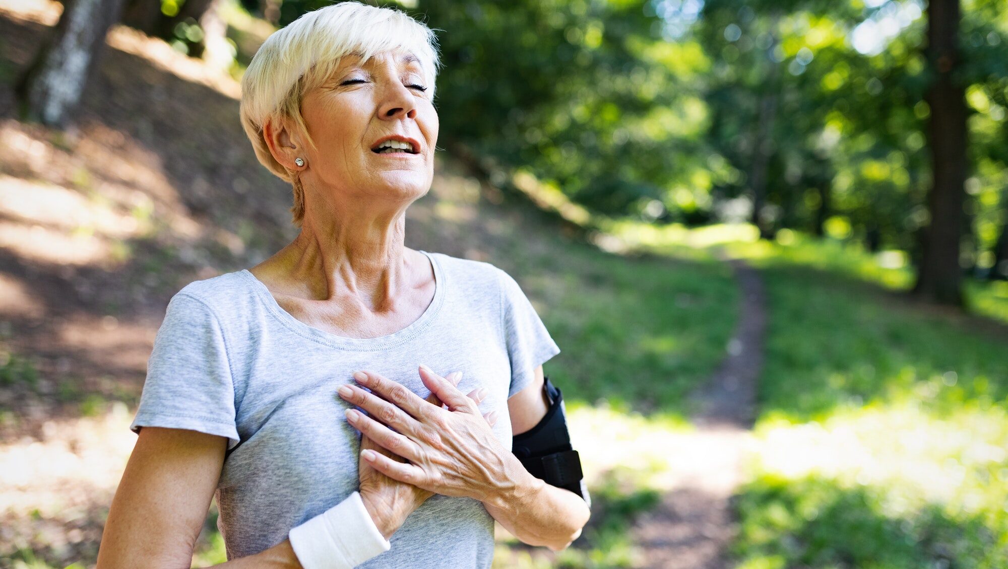 Äldre kvinna som tränar och får en hjärtinfarkt